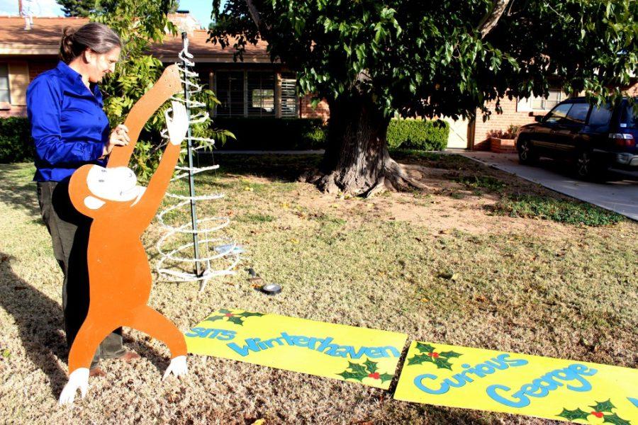 Janete, resident of Winterhven, sets up her Curious George display that reads Curious George visits Winterhaven on her yard on Friday, Dec. 2 in Tucson, Ariz.