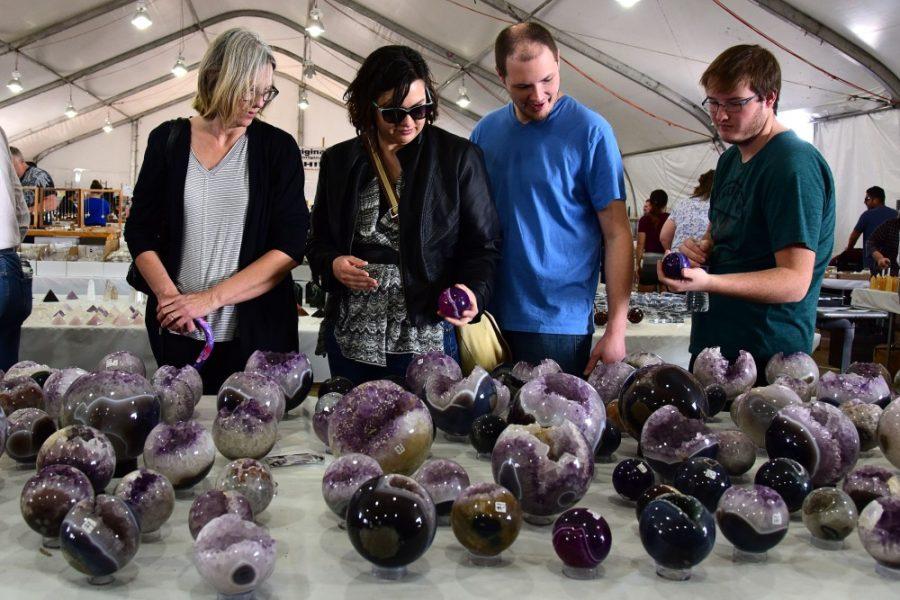 Leah Martinez, center left, examines an amethyst sphere in the Village Originals, Inc. at the Kino Gem Show during the annual Tucson Gem and Mineral Show on Saturday, Feb. 4, 2017. Martinez, a Tucson native, attends the show almost every year and made a wind chime out of a unique collection of rocks from the show as a mothers day gift last year. 