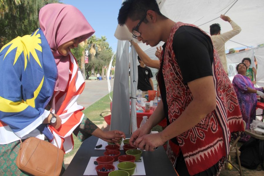 The Flavor of Malaysia was not limited to food. Nurfathiah Nasution, Left, and Ryan Sigat, right, play the Malaysian game Congkak while sporting traditional Malaysian clothing.