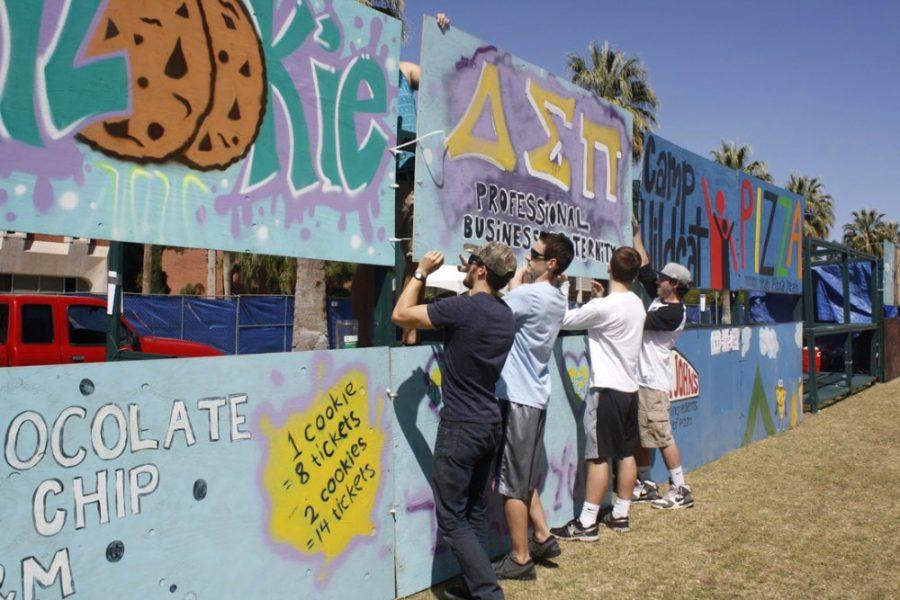 <p>Delta Sigma Phi fraternity members and volunteers work to hang up booth signs for 2015's Spring Fling. All concessions at the event are sold by student groups, which receive a share of proceeds following the festival.</p>