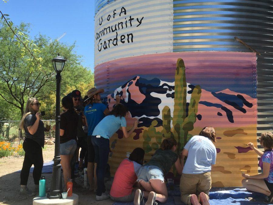 A group of people paint the cistern in the UA Community Garden on April 15. The cistern collects rainwater to be used to water plants in the garden and surrounding area.