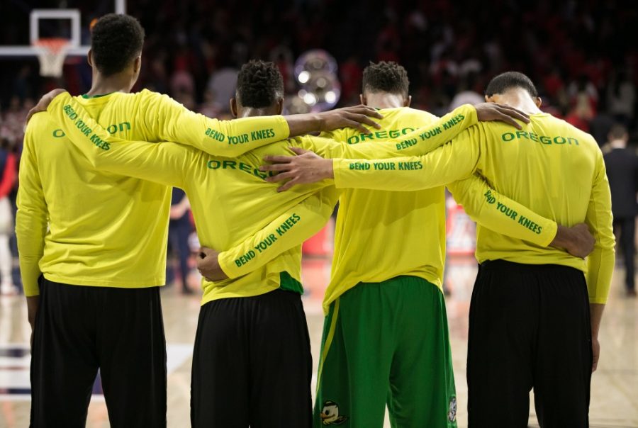 Members of the Oregon Mens Basketball team link arms during the National Anthem in McKale Center.