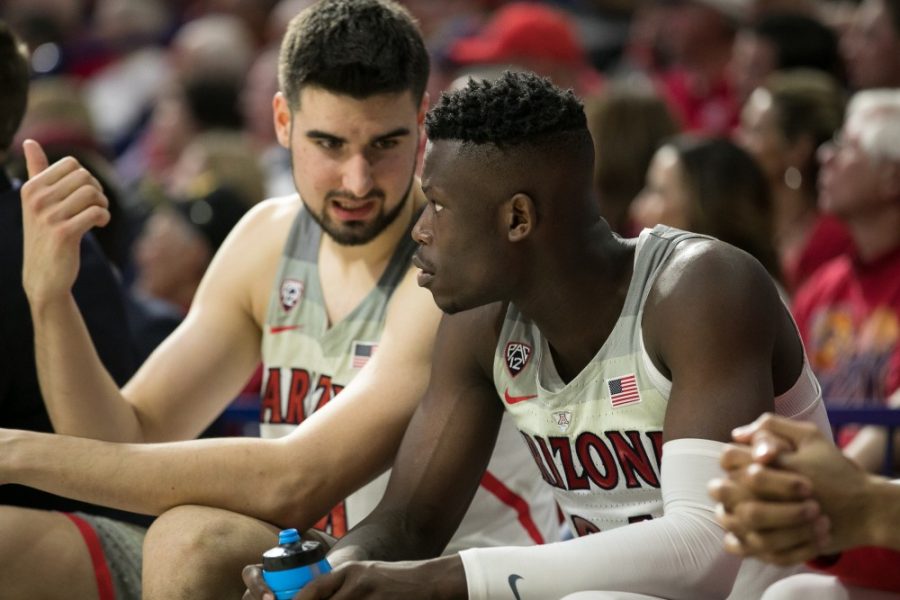 Arizonas Emmanuel Akot, right, and Dusan Ristic, left, share a word on the bench while watching their teammates down the court.