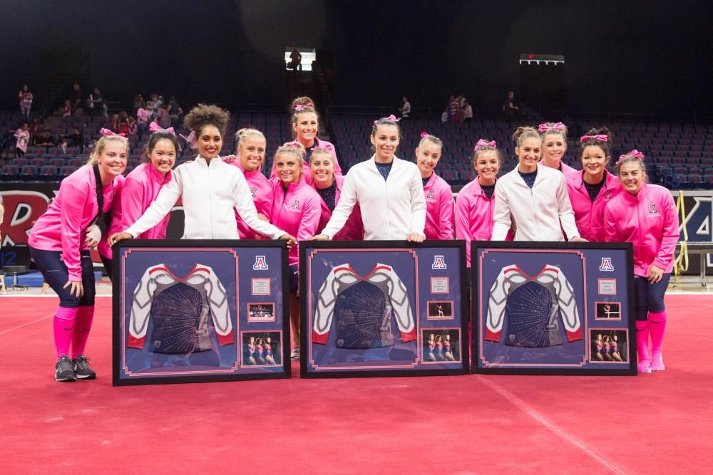The UA Gymnastics team gathers around the three UA Gymnastics seniors, Kennady Schneider, Victoria Ortiz, and Madison Cindric, as they hold their farewell gifts during the UA v Stanford meet on Jan. 11 in Mckale Center.