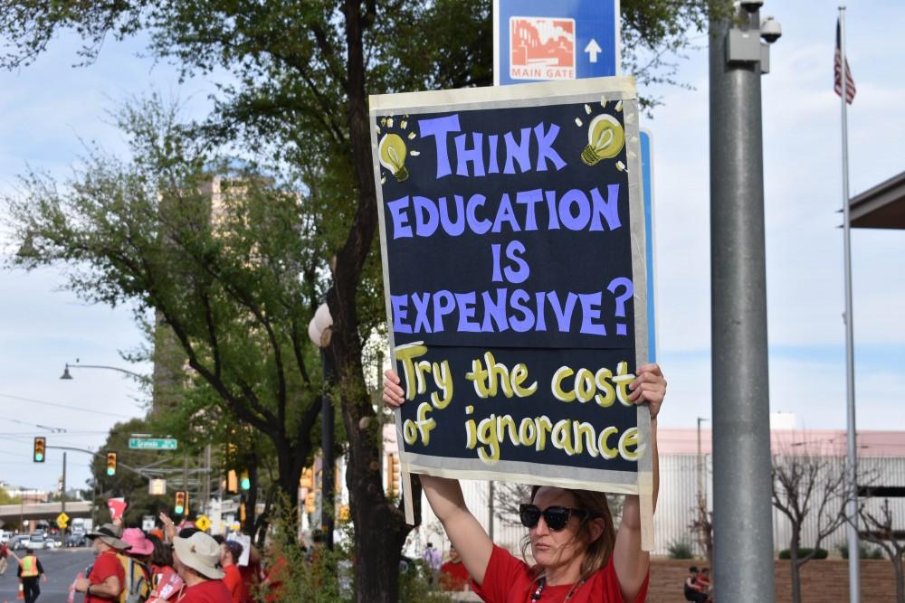 A teacher holds up a sign that says, “Think education is expensive? Try the cost of ignorance” during the RED for ED protest on April 4 in downtown Tucson.