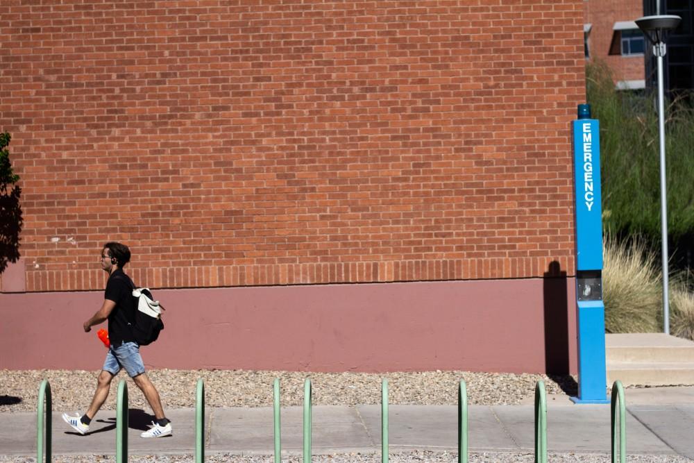 A student walks past one of many Emergency Blue Light Telephones located on the University of Arizona Campus on May 15, 2018. The UA installed EBLTs so students would be able to press a large emergency button to immediately alert UAPD of imminent danger to themselves or another person, or any other criminal activity in the area. 
