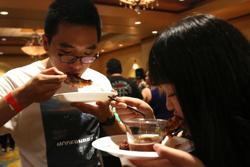 UA Students, Gerry Sun and Iris Li, bite into their BBQ chicken from the Frog and Firkin. Both college students enjoyed all the free food at the 2nd Annual Main Square Culinary Challenge  at the Marriott Tucson University Park Hotel. 