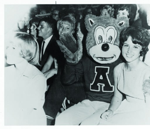 Wilbur Wildcat, mascot of the University of Arizona athletic teams, and a female friend sitting among a group of students in the 1960s.