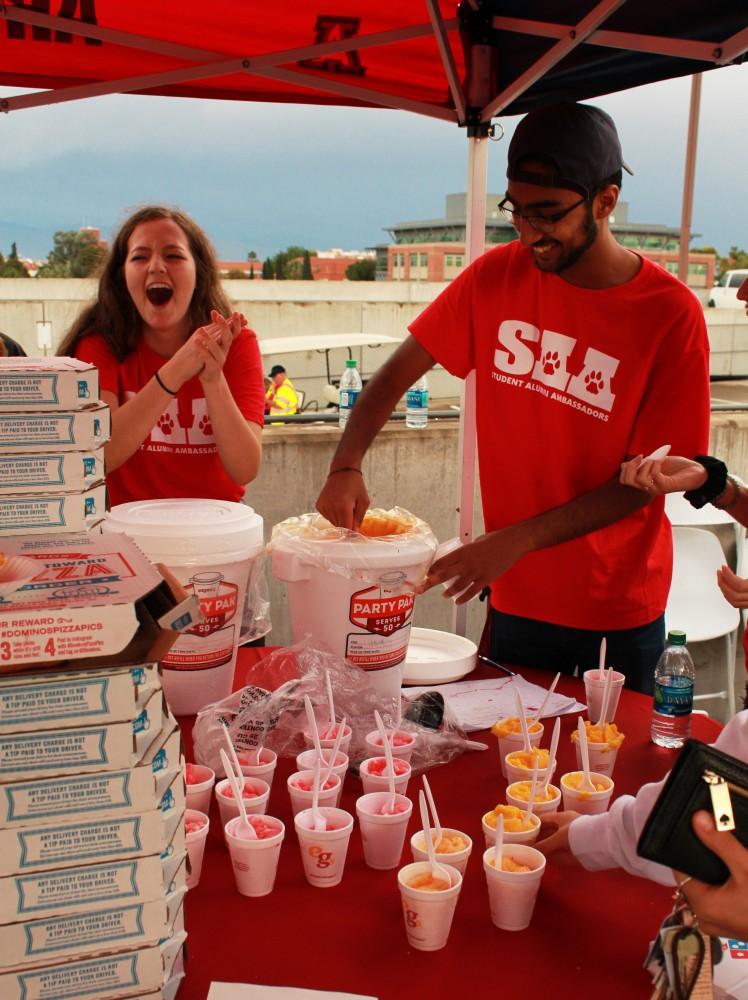 Volunteers with the University of Arizona student alumni association provide free Eegees and pizza at the Main Gate Square watch party for the lighting of A mountain on Sunday. The "A" on Sentinel Peak was constructed in 1916.