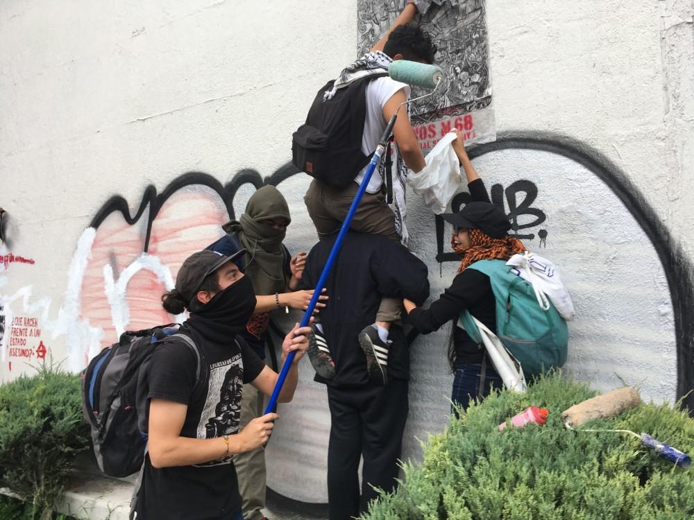 On Tuesday, Oct. 2, a group of UNAM students in Tlatelolco, Mexico City paste a print commemorating those killed in the 1968 student movement  before joining in a city wide march. Students covered the walls of  Tlatelolco buildings with messages about the 1968 movement, the 43 Ayotzinapa students who were disappeared in 2014, and the porro attack at UNAM in September.