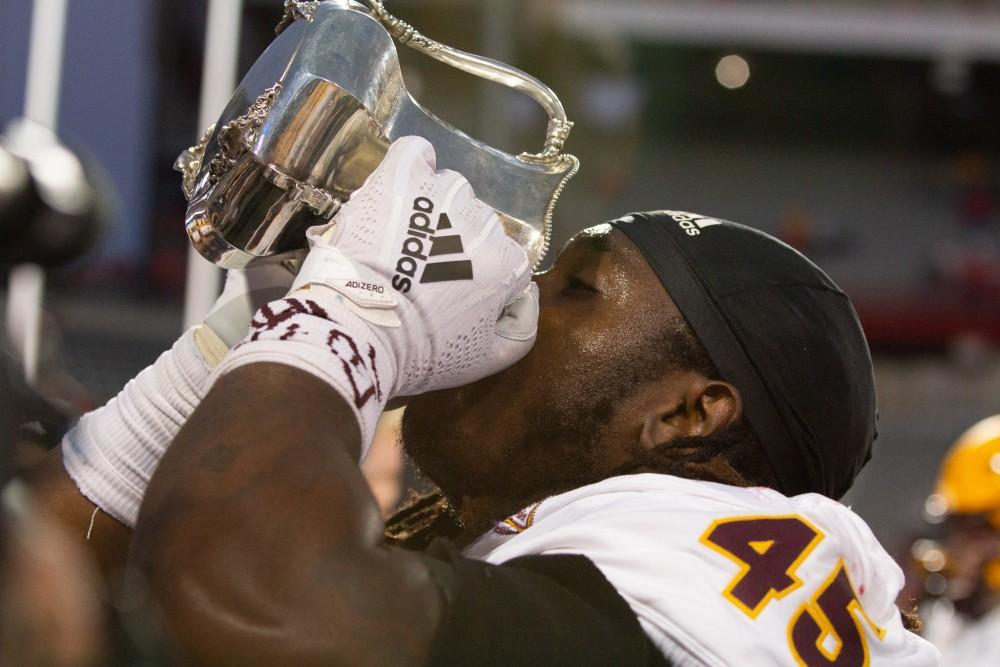 An ASU player pretends to drink out of the territorial cup after beating Arizona 41-40 on Saturday, Nov. 14 at Arizona Stadium. 