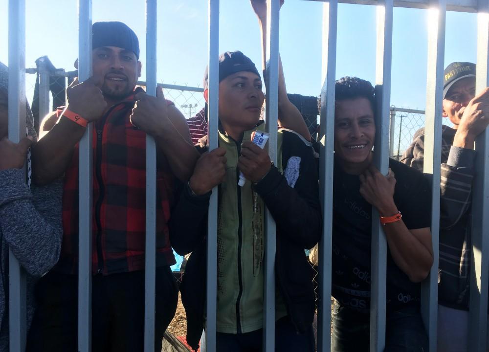 A group of men smile a the camera during the migrant caravan. 