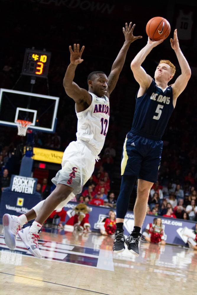 Guard Justin Coleman (12) jumps to block a UC Davis player from taking a shot during the game on Saturday, Dec. 22 at McKale Center. Arizona won the game with a final score of 70-68. 