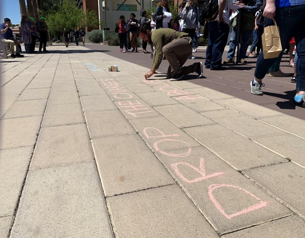 Students and other members of the campus community gathered on April 11 to protest at the Arizona Board of Regents meeting. Before the start of the meeting, members of the silent protest wrote "drop the charges" on the ground in chalk. 