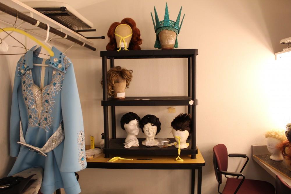Some of the wigs the actors have to wear throughout the show are displayed on a shelf in the men’s dressing room.