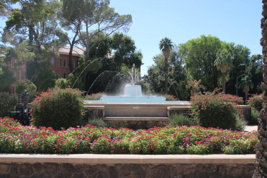 At the front entrance of the University of Arizona is a large water fountain surrounded by a dozen different types of flowers.