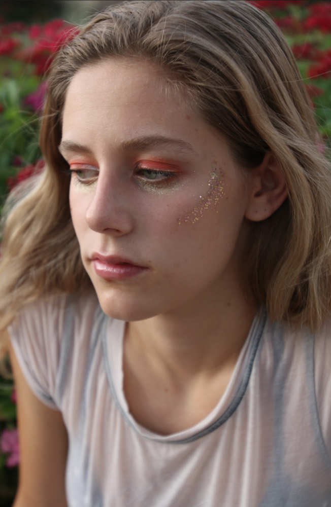 UA Photography major Tia Stephens wears a bright makeup look inspired by Euphoria. She created the look with glitter and bright shades of orange eyeshadows.