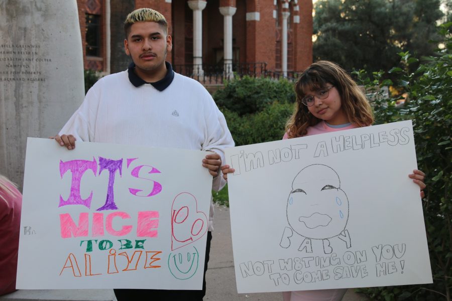 Victor Martinez and Nicole Martinez hold up signs they created before the SlutWalk 2019 march. Students were invited before the Slut Walk to meet and create signs at the Womens Plaza of Honor on campus.