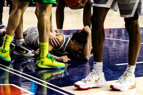 After attempting to dunk the ball into the basket, Josh Green (0) falls to the ground in pain.