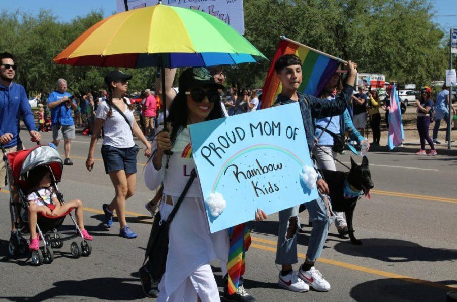 Tucson Pride attendee walks down Country Club Road in 2019, holding a sign in support of the LGBTQ+ community.  