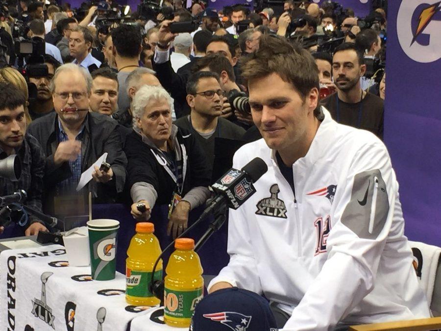 Tampa Bay Buccaneers quarterback Tom Brady sits at the podium and answers questions from the media ahead of Super Bowl 49 in Phoenix, Ariz., in February of 2014. Tom Brady responds to reporters at Media Day by WEBN-TV is licensed under CC BY-ND 2.0