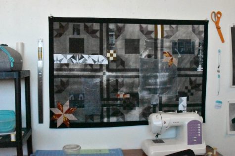A sewing machine sits in front of a quilted artwork hanging in Jesse Hinson's studio. Hinson works with textiles and things that relate to craft histories, bringing attention to domesticity and the history of women in the home.