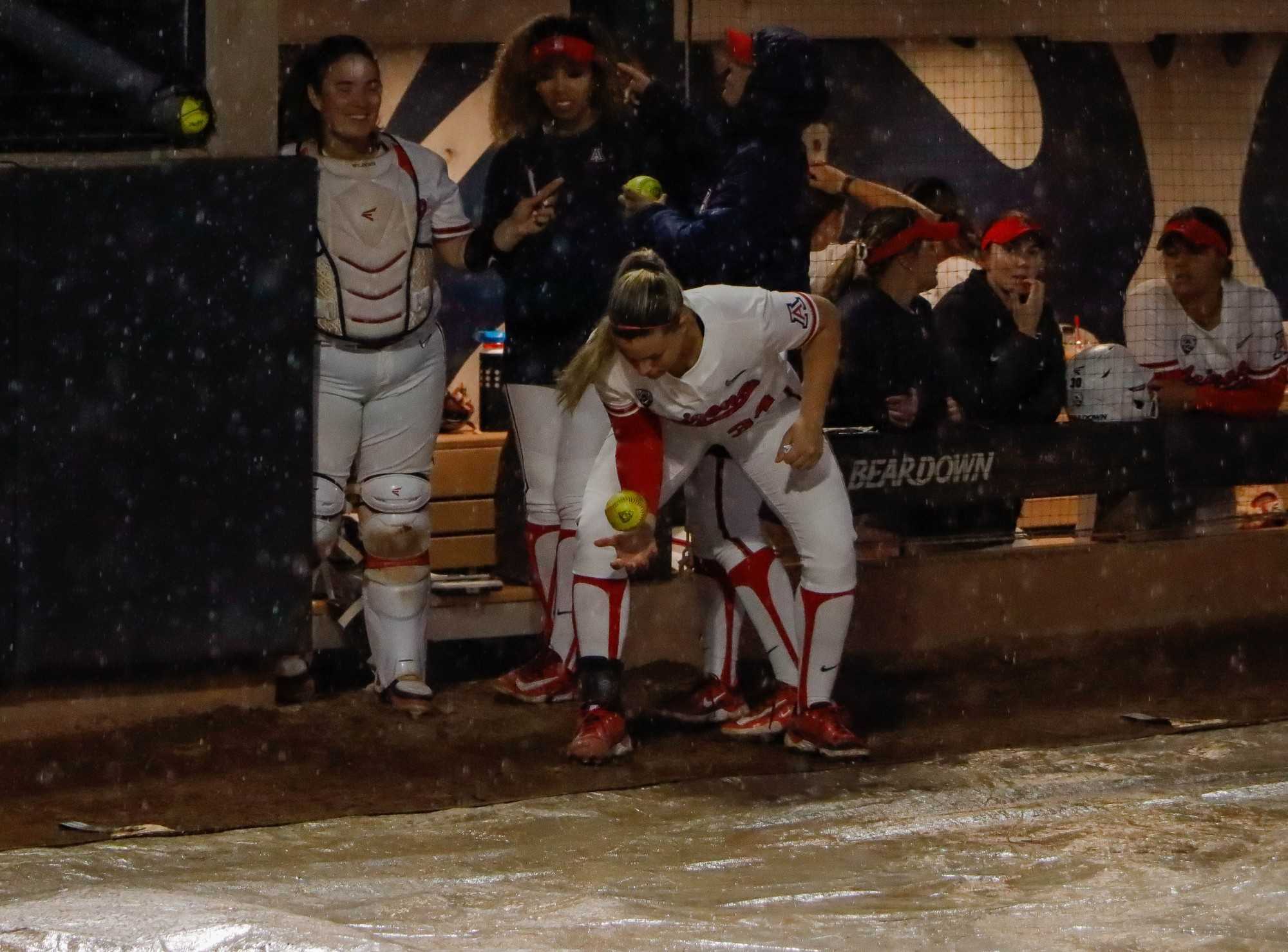 Arizona softball players (pictured left to right) Izzy Pacho, Brianna Hardy and Devyn Netz talk to the New Mexico State University players during a rain delay by throwing a ball back and forth with writing on it in Rita Hillenbrand Memorial Stadium on March 15. Arizona won both games against New Mexico, winning the first game by 10 runs and the second game by 8 runs. 