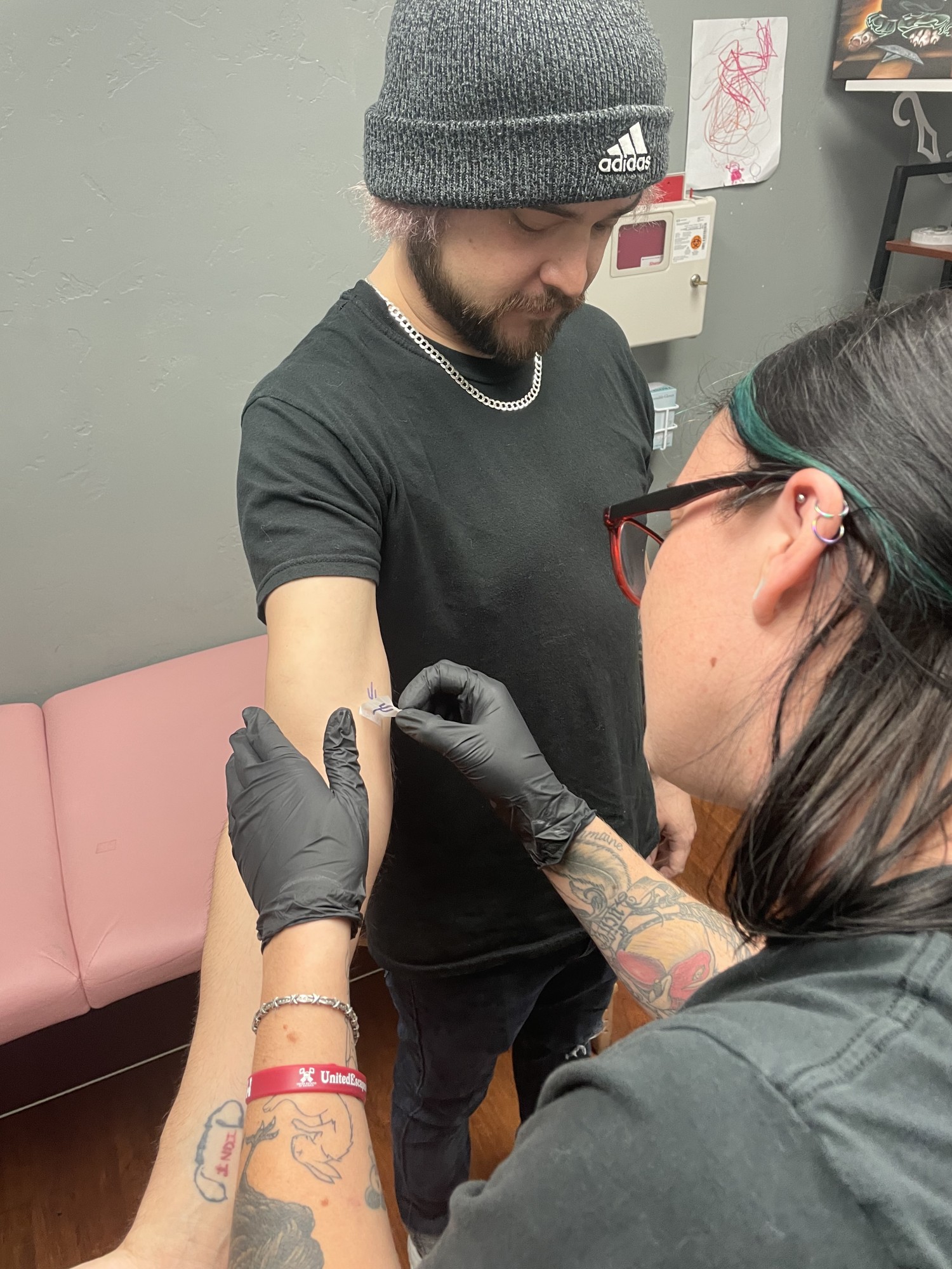 Tattoo apprentice Rhi Drennan applies the stencil onto her client’s arm. 