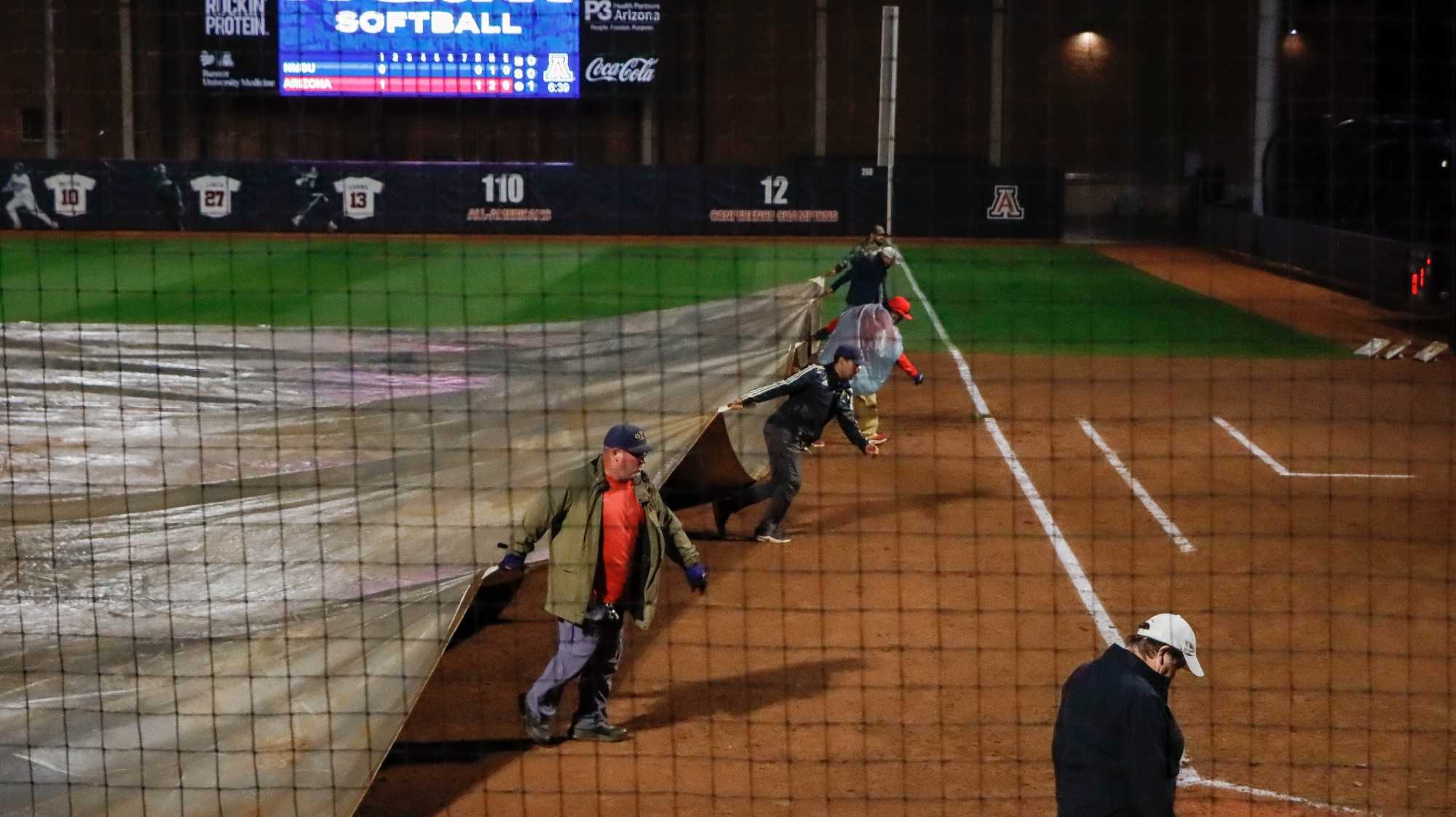 Arizona softball grounds crew covers the field during a rain delay in Rita Hillenbrand Memorial Stadium on March 15. The rain delay lasted approximately 30 minutes until the Umpires deemed it safe to resume play.  