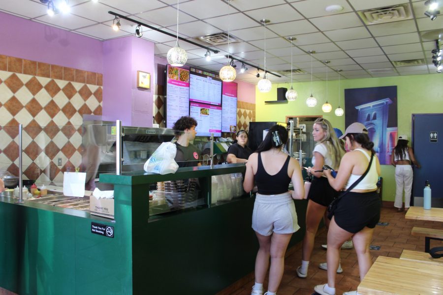Students order food inside Jimmys Pita & Poke on University Boulevard on March 29. The inside of the restaurant is colorful and bright, matching the colorful ingredients on display. 