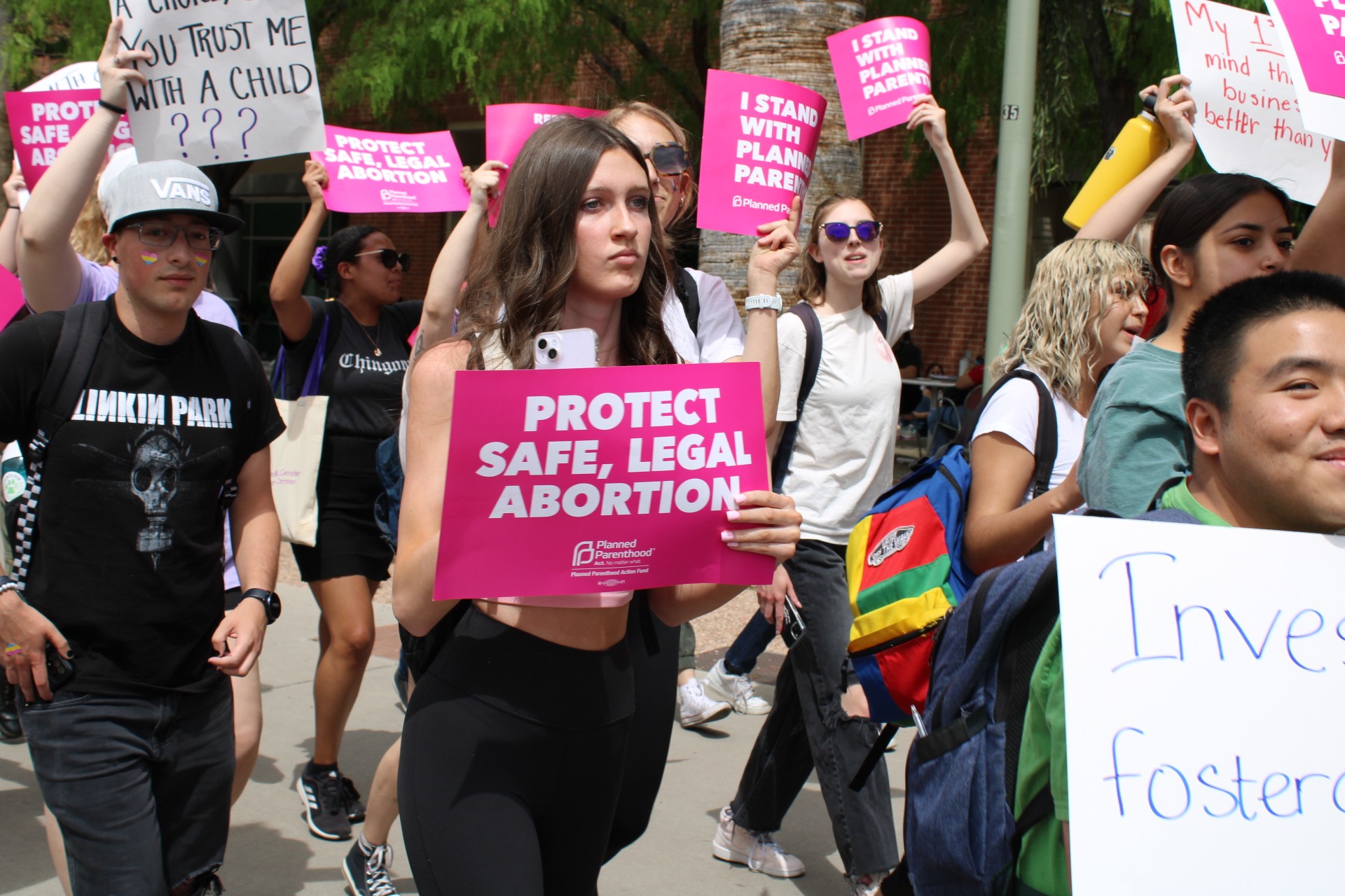 A crowd of University of Arizona students and community members march along the middle of campus, holding signs in support of pro-choice on Thursday, April 13. The protest was held to counter the anti-abortion group that set up a demonstration on the UA Mall for two consecutive days displaying large, graphic images of blood and dead people.