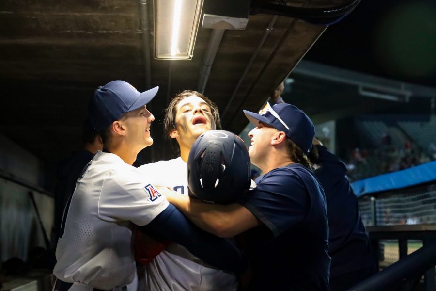 Cameron LaLiberte (left) and Jack Grant (right) hug Tony Bullard (center) after he scores a run in a game against Utah on April 21 at Hi Corbett Field. The Wildcats went on to win the game 14-9. 