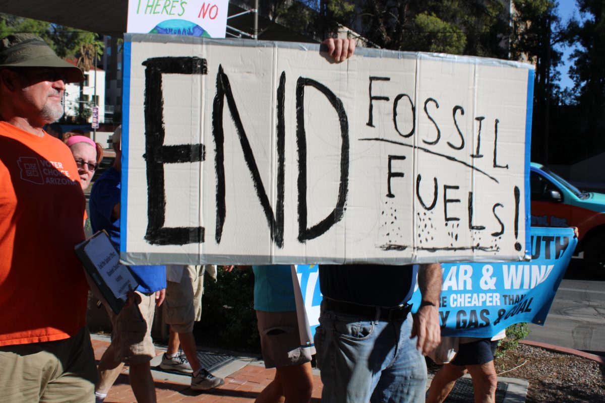 A protestor holds up a sign reading end fossil fuels!
