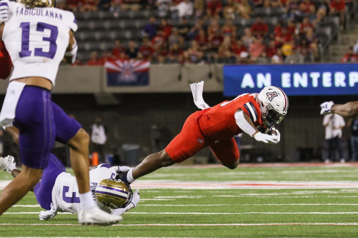 Arizona running back DJ Williams is tripped up by a Washington defender in a narrow home loss on Sept. 30 in Tucson. The Wildcats lost the game 24-31.