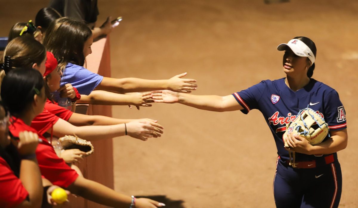 Aissa Silva greets fans while warming up for the second game of the night at Mike Candrea Field at Rita Hillenbrand Memorial Stadium on Friday, Oct. 13. Arizona won 10-0 against Eastern Arizona College to cap off a doubleheader.