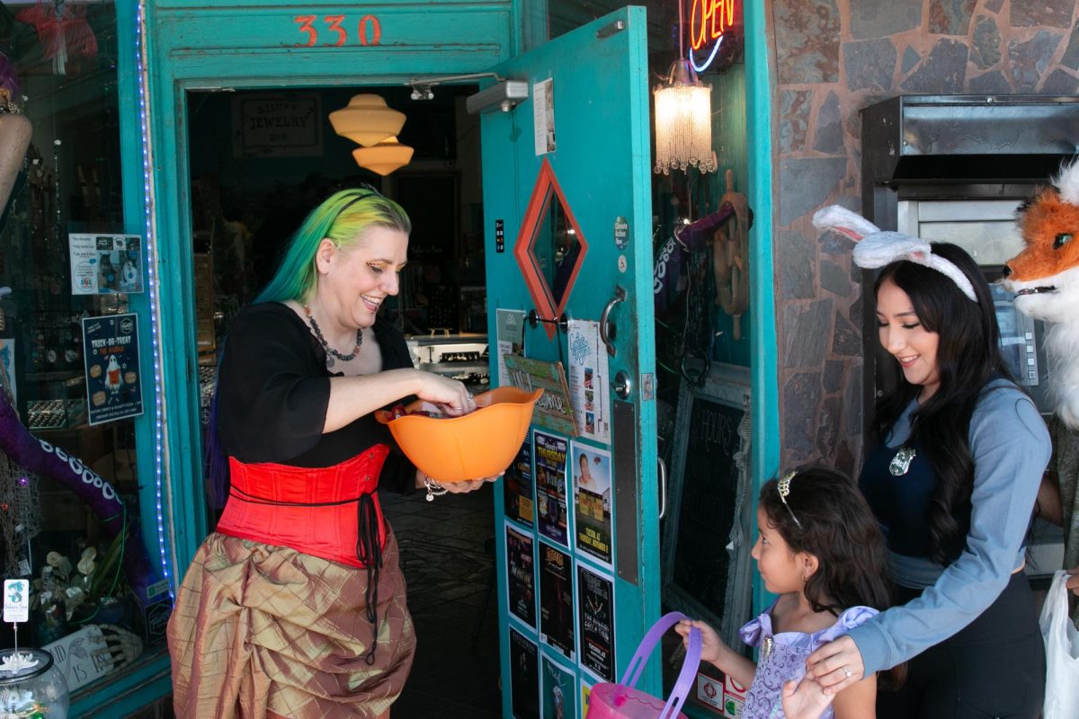 Lizzie Mead hands candy to a trick-or-treater outside of Silver Sea Jewelry during Trick-Or-Treat the Avenue on Fourth Avenue on Oct. 29. Mead spent the afternoon handing out candy and compliments to many of the trick-or-treaters.
