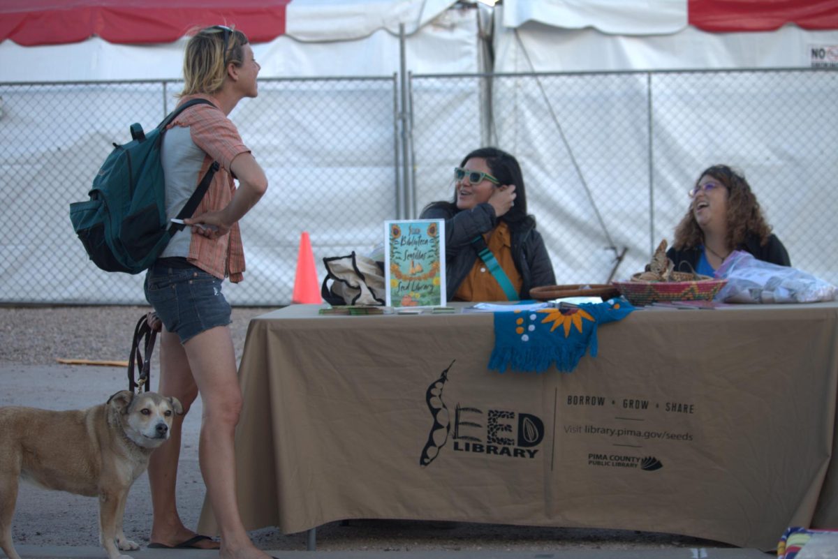 Volunteers and staff from the Pima Community Library table at the MSA Annex Farmers Market on the first Thursday of the month. At the table is an assortment of seeds and educational materials about seed swapping.