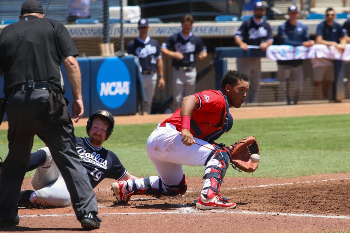 Arizona catcher Adonys Guzman tries to tag out the runner sliding into home against Dallas Baptist during the Tucson Regional of the NCAA Baseball Tournament on June 1 at Hi Corbett Field. Arizona would lose the game 7-0.