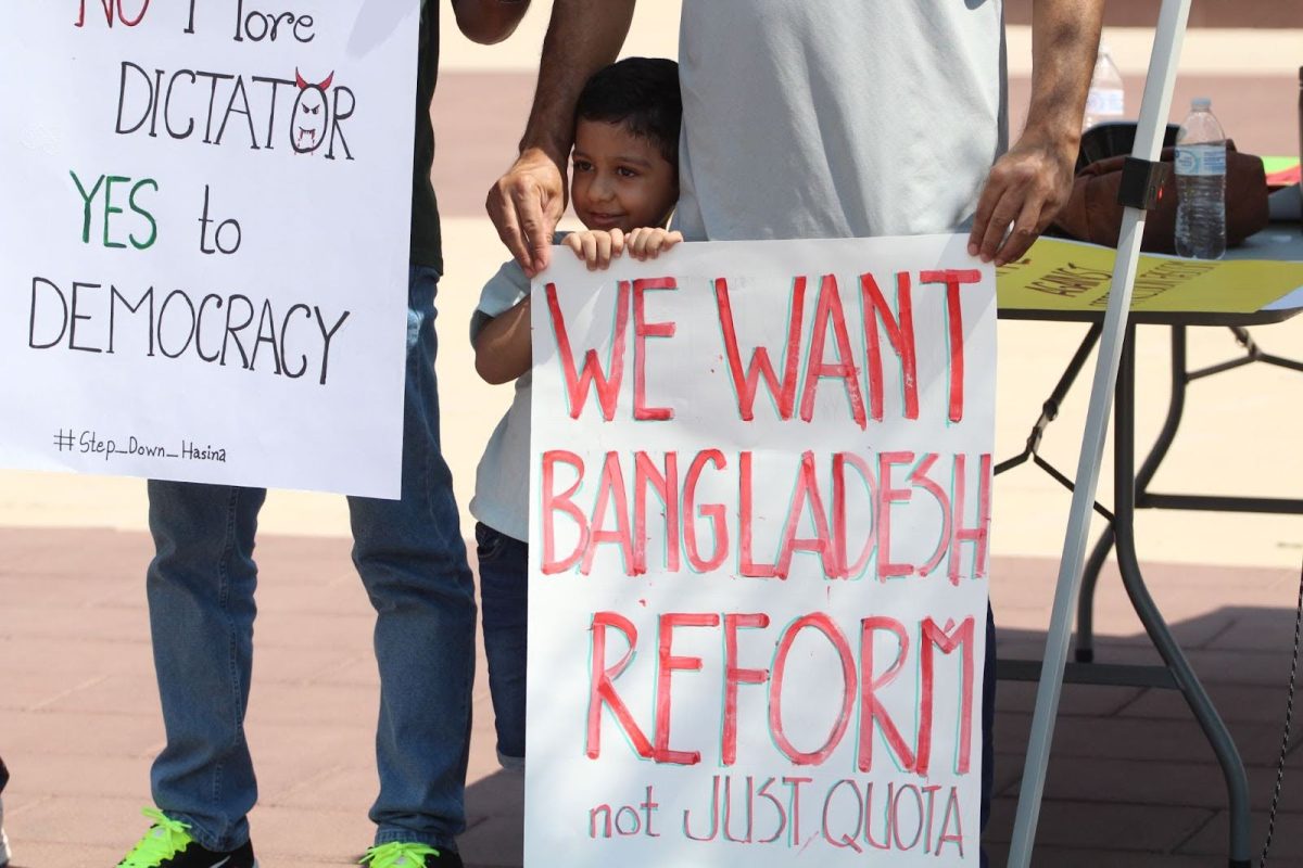 A child helps hold a protest poster on July 24. The poster calls for reform, not just quota, in Bangladesh.