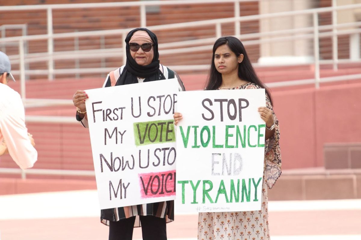 Two protesters stand together for a photo on July 24. They hold two signs to protest the killings of protesters in Bangladesh.