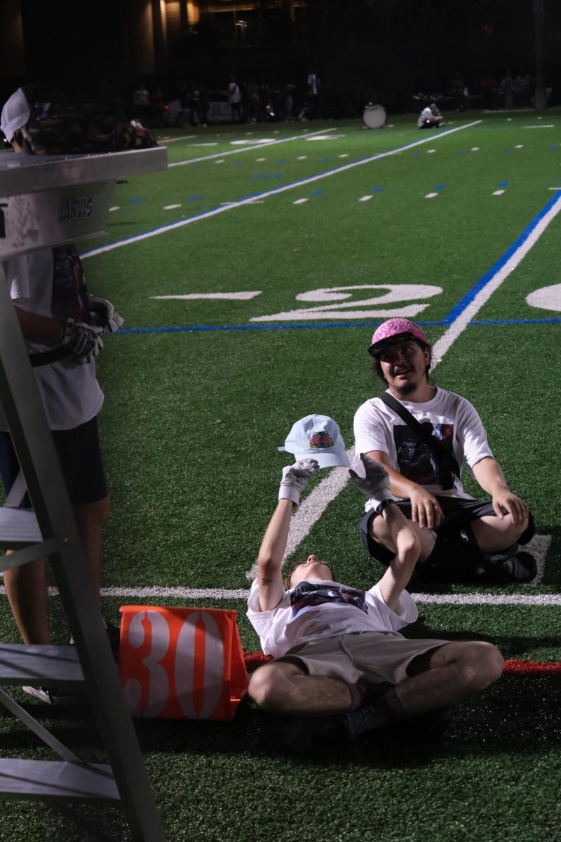 Members of the Pride of Arizona lay exhausted in between movements during their practice at Bear Down Field on Aug. 23. The band had been practicing for hours before their full performance.