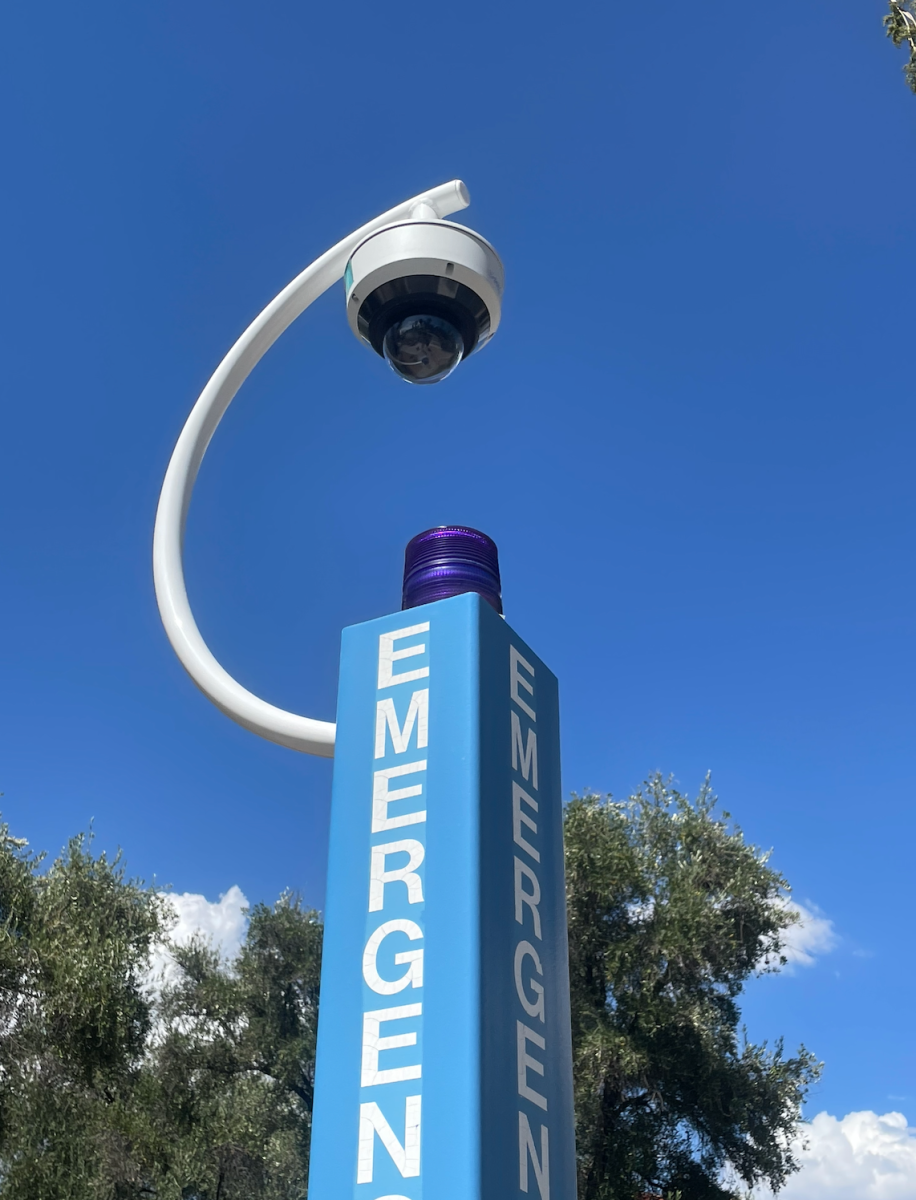 One of the new blue light emergency phones and security camera installations sits outside of Old Main on a sunny afternoon.  The inclusion of these cameras is one of the security upgrades to campus this semester.
