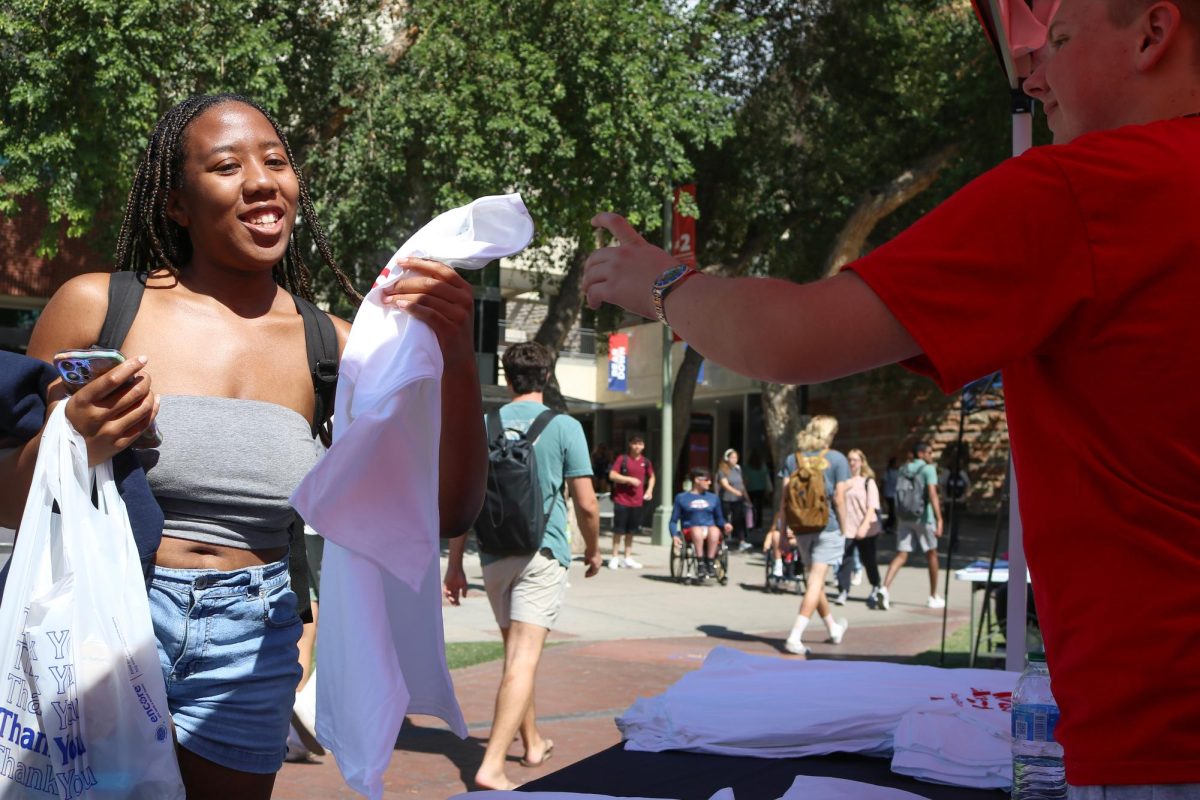 A student picks up a free T-shirt from the Wildcat Events Board on the UA Mall on Oct. 10. WEB served free pizza to students stopping by as well.