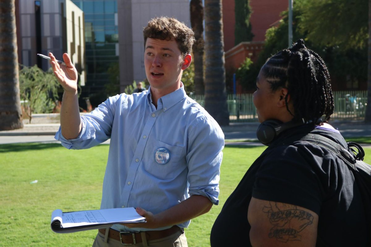 A student with the Arizona for Harris campaign helps with voter education on the UA Mall on Oct. 15. The student on the right was in line to meet U.S. Senator Mark Kelly.