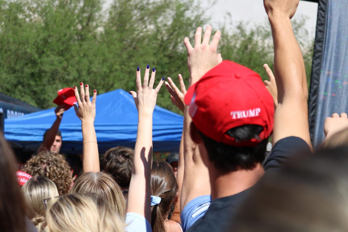 Students raise their hands awaiting Charlie Kirk to throw a MAGA hat toward them on Oct. 16 by the student union. Kirk was joined by Tulsi Gabbard and Bryce Hall.