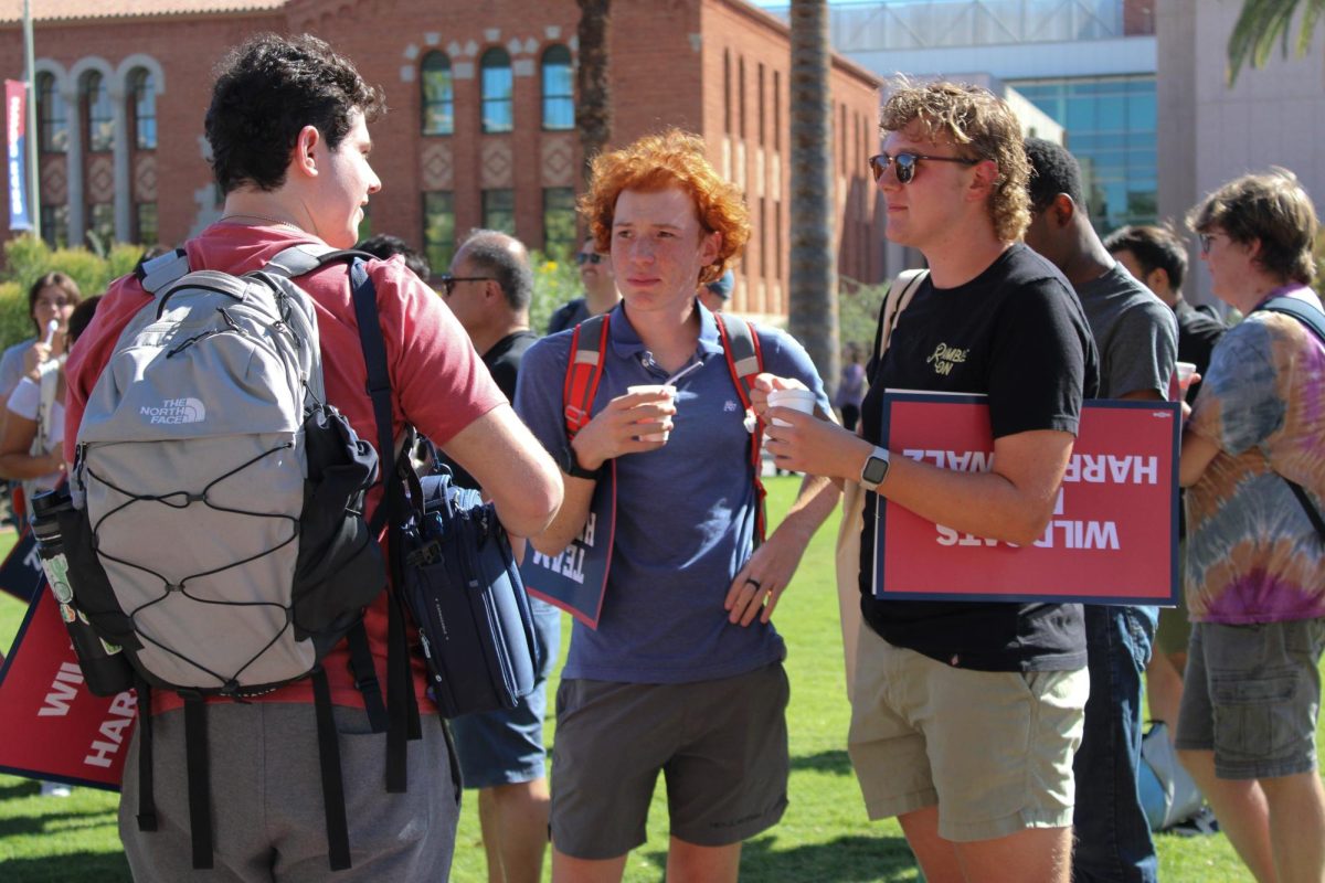 Three students talk to each other as they wait to meet U.S. Senator Mark Kelly on Oct. 15. The University of Arizona Mall held a meet and greet where a former ASUA student body president introduced Kelly.