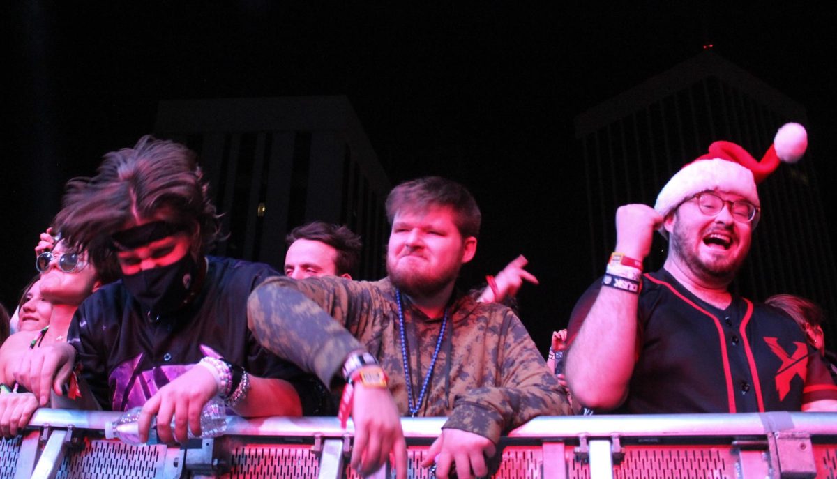 Three festival-goers dance on the rail during ATLiens set at DUSK Music Festival in Downtown Tucson on Nov. 10. The three jump and "head bang" over the rail. 