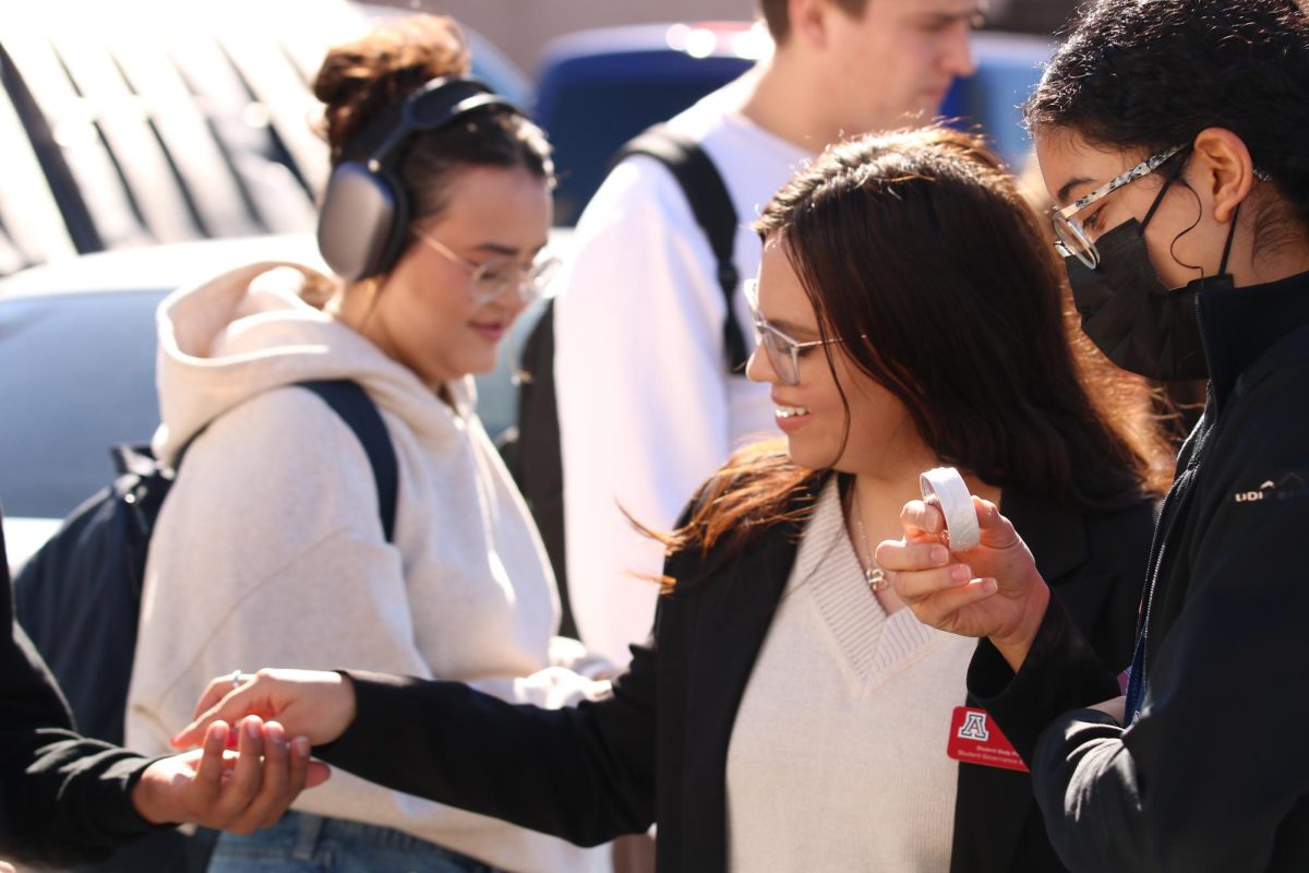 ASUA President Adriana Grijalva hands out pins and stickers to voters in line at First United Methodist Church on Nov. 5. The goodies read "Wildcats take action."