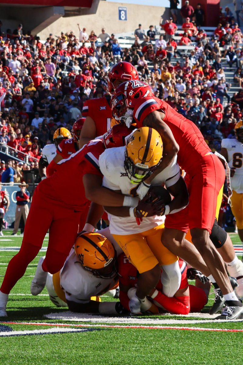 Arizona defensive backs Tacario Davis (1) and Dalton Johnson (43) tackle an Arizona State player at the 20 yard line.