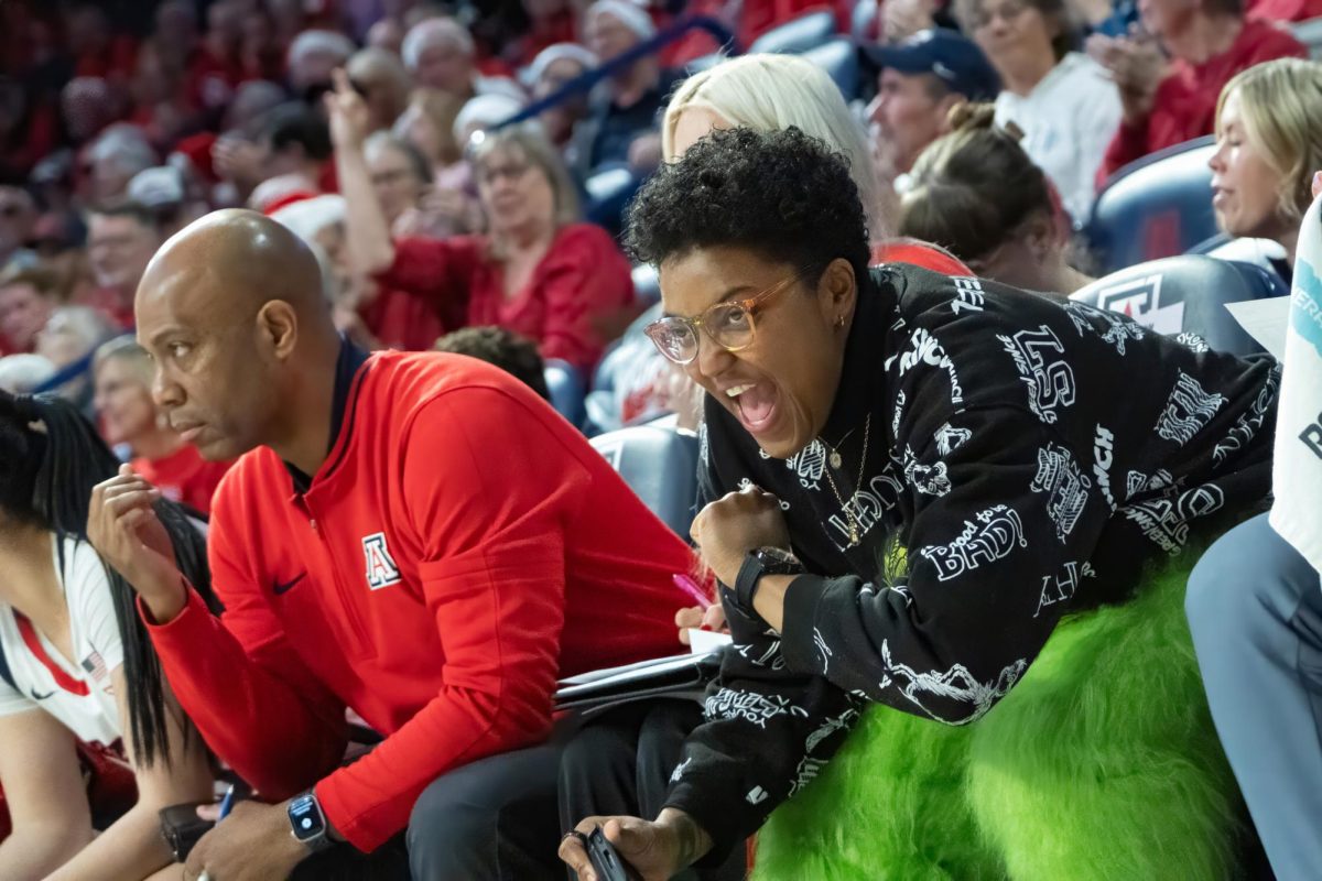 Kamiko Williams, dressed as the Grinch cheers on the Arizona Wildcats during their game against Weber State on Dec. 16 in McKale. The game was an overwhelming victory for the Wildcats with a final score of 66-87.